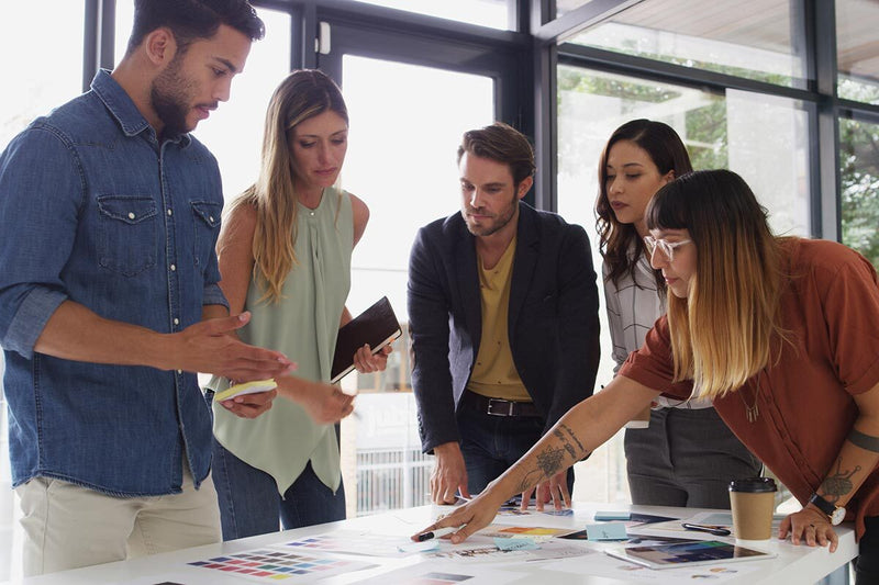 Group of people collaborating around a table with design materials in an office setting